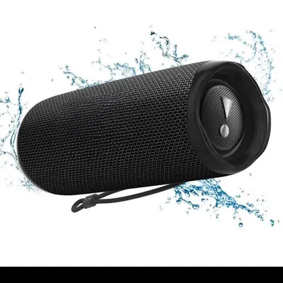 A black cylindrical portable speaker with a mesh body and a wrist strap, shot against white with a splash of water frozen behind it