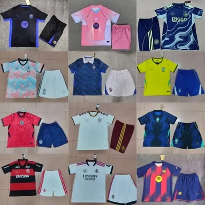Twelve football kits laid out on a tiled floor in a grid, each one a shirt beside matching shorts, in blue, pink, yellow, red, white and black, every set still carrying its hang tag