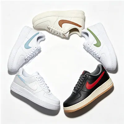 Five low-top trainers arranged in a ring on a white background, four in white leather with tan, pale blue and green side marks, one in black with a red mark and a gum sole